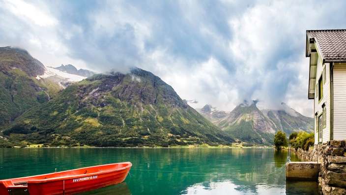 Ein kleines rotes Boot auf einem See mit einem Berg im Hintergrund