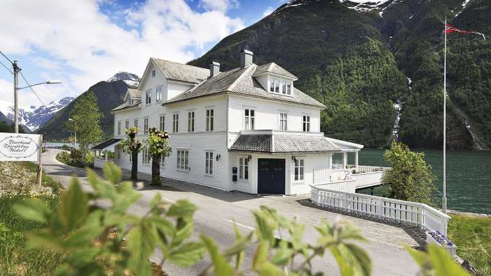 Ein großes weißes Haus mit einem Schild davor, das sagt fjordland hotel