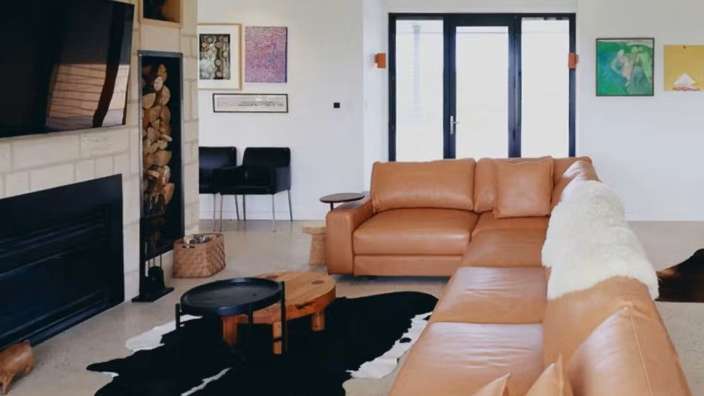 Ein Wohnzimmer mit einem braunen Ledersofa und einem schwarz-weißen Teppich