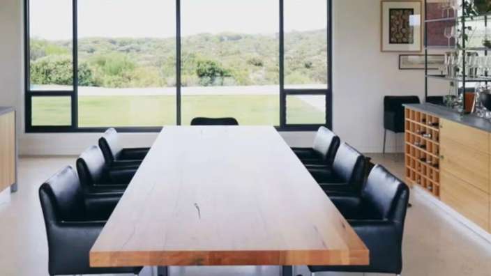 Ein Esszimmer mit einem langen Holztisch und schwarzen Stühlen