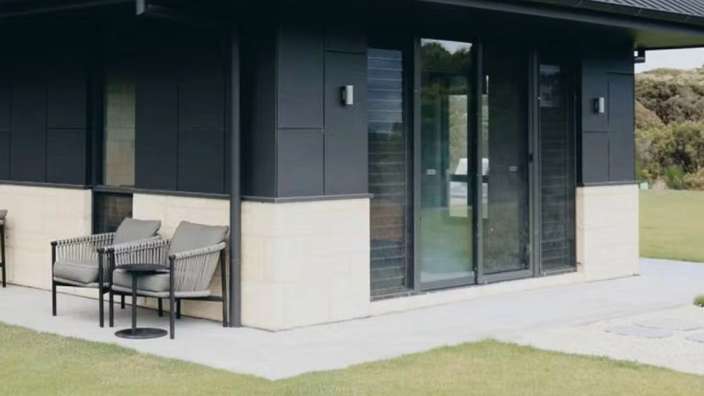 Ein schwarzes Haus mit zwei Stühlen und einem Tisch davor