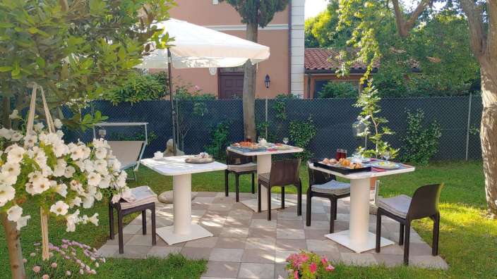 Tische und Stühle stehen auf einer Terrasse im Garten