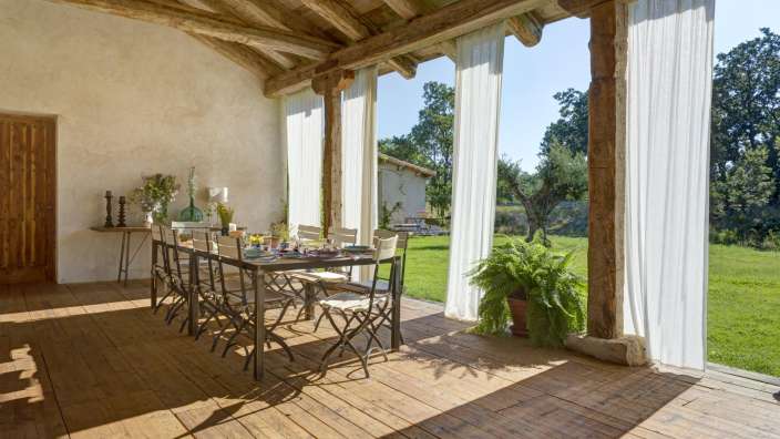Ein Tisch und Stühle auf einer Veranda mit weißen Vorhängen