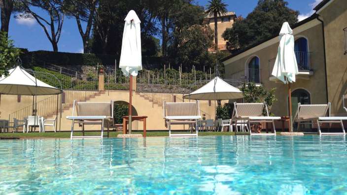 Liegestühle und Sonnenschirme umgeben einen großen Swimmingpool