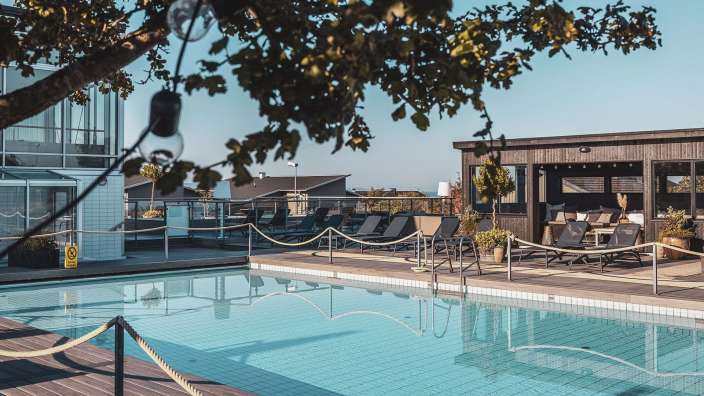 Ein großer Swimmingpool mit Liegestühlen und einem Gebäude im Hintergrund