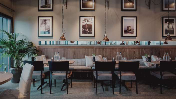 Eine Reihe von Tischen und Stühlen in einem Restaurant mit Bildern an der Wand