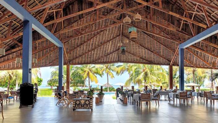 Ein großer Raum mit Tisch und Stühlen unter einem Strohdach