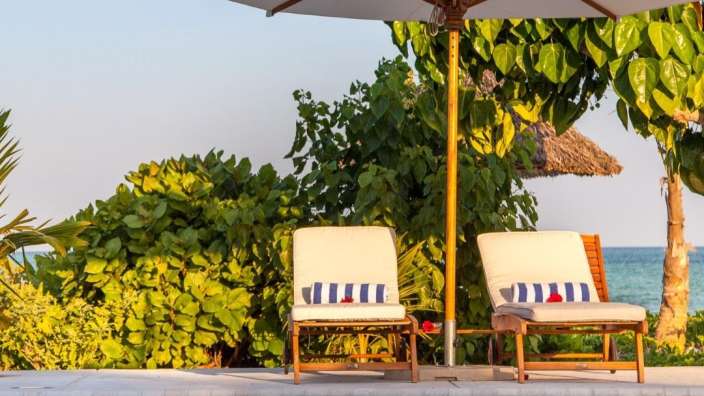 Zwei Liegestühle neben einem Pool mit einem weißen Regenschirm