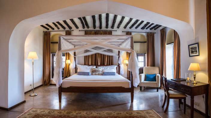 Ein Schlafzimmer mit einem Himmelbett und einem Stuhl