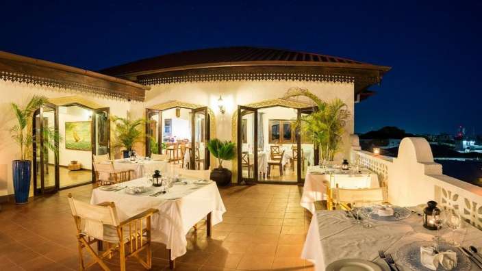 Ein Restaurant mit weißen Tischen und Stühlen bei Nacht