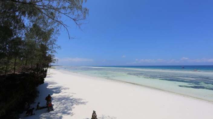 Eine Gruppe von Menschen steht an einem weißen Sandstrand