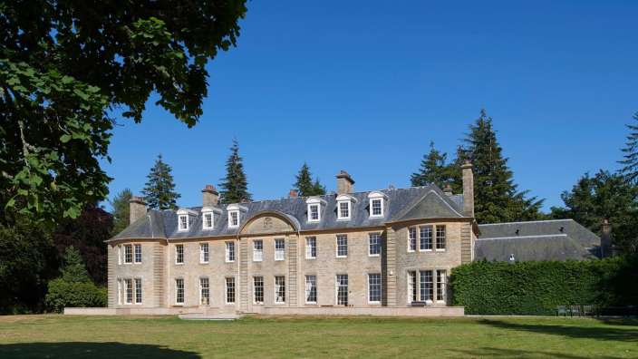Ein großes Steingebäude mit vielen Fenstern und einem blauen Himmel dahinter