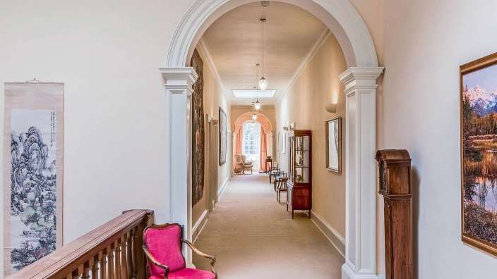 Ein Flur mit einem roten Stuhl und einem Gemälde an der Wand