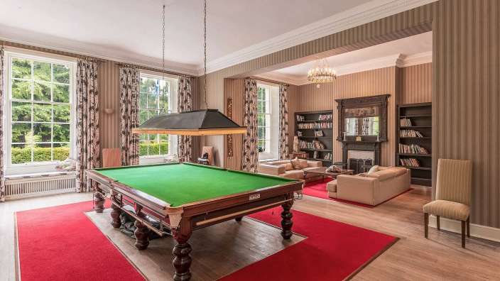 Ein Pooltisch in einem Wohnzimmer mit einem roten Teppich