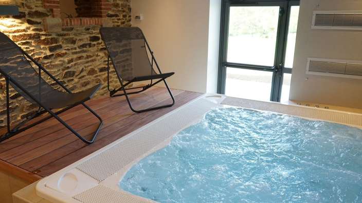 Ein Whirlpool mit blauem Wasser und zwei Stühlen davor