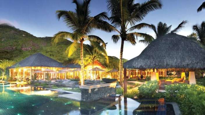 Ein großer Swimmingpool umgeben von Palmen und Hütten