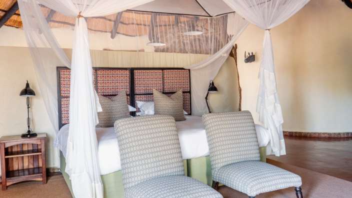 Ein Schlafzimmer mit Himmelbett und zwei Stühlen