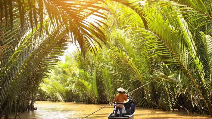 Ein Mann paddelt in einem kleinen Boot auf einem Fluss