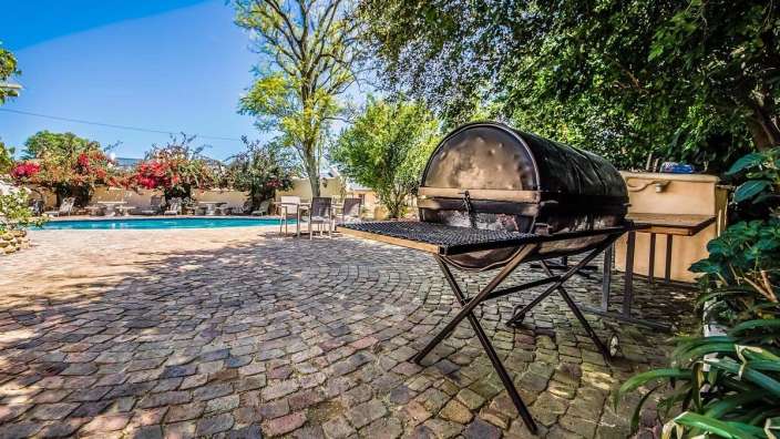 Ein Grill steht auf einem Backsteinterrassen neben einem Pool