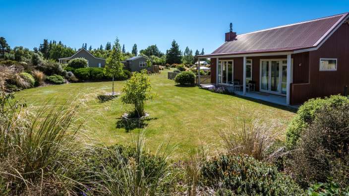 Ein rotes Haus mit einem roten Dach sitzt auf einem grünen Rasen