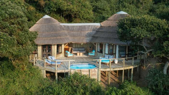 Ein Haus mit Strohdach und einem Pool auf einem Holzdeck