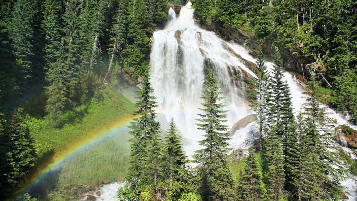 Ein Wasserfall im Wald mit einem Regenbogen davor