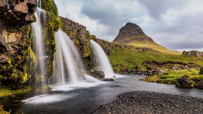 Ein Wasserfall mit einem Berg im Hintergrund