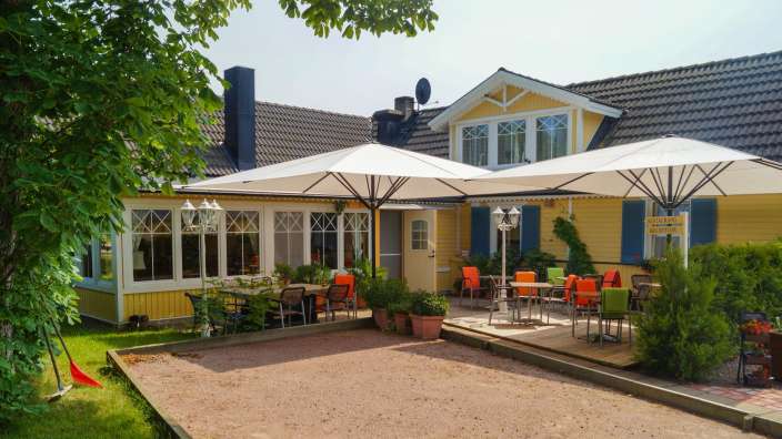 Ein gelbes Haus mit blauen Fensterläden und weißen Sonnenschirmen