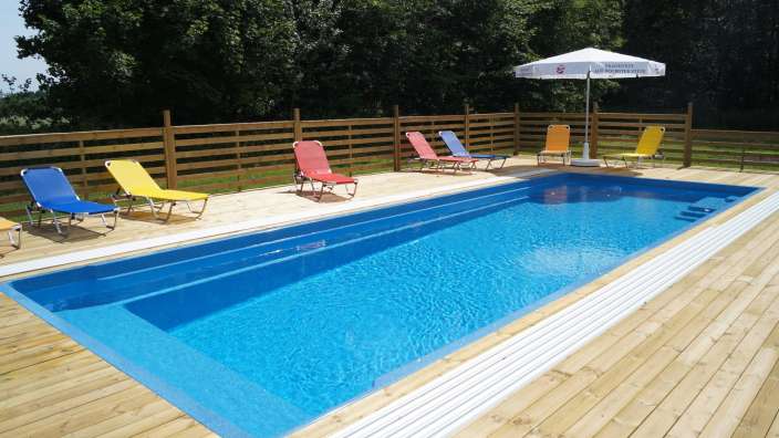 Ein blauer Pool mit Liegestühlen und einem weißen Regenschirm