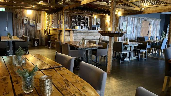 Ein Restaurant mit Holztischen und Stühlen und einer Bar