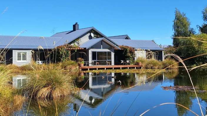 Ein Haus steht neben einem Teich mit Enten im Wasser
