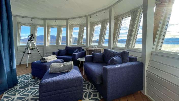Ein Wohnzimmer mit blauen Möbeln und vielen Fenstern
