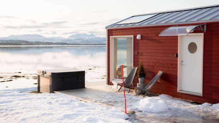Ein kleines rotes Haus neben einem See