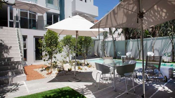 Eine Terrasse mit Tisch und Stühlen und Sonnenschirmen