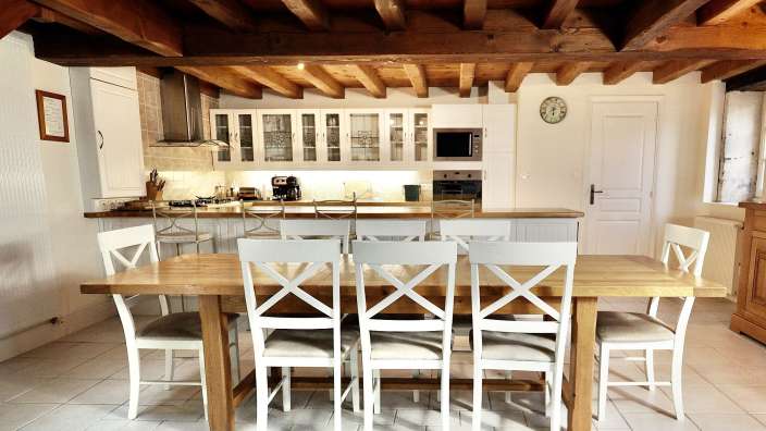 Eine Küche mit einem Holztisch und weißen Stühlen