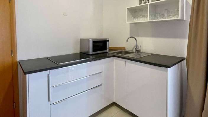 Eine kleine Küche mit weißen Schränken und einem Mikrowellenherd