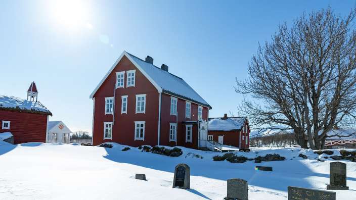 Ein rotes haus mit weißen fenstern steht im schneebedeckten dorf