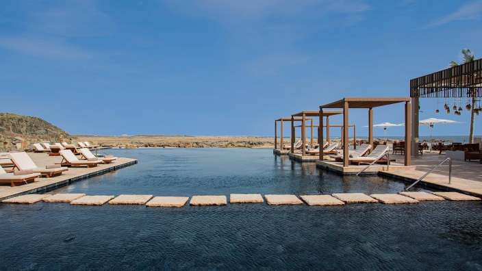 Ein großer Pool mit Liegestühlen und Sonnenschirmen umgeben