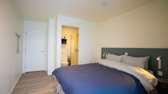 Ein Schlafzimmer mit einem blauen Bett und weißen Kissen