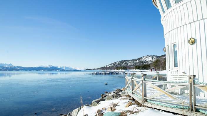Ein weißes Gebäude neben einem See mit schneebedeckten Bergen im Hintergrund