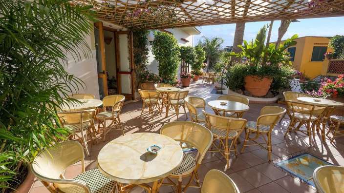 Eine Terrasse mit Tischen und Stühlen und einer Pergola