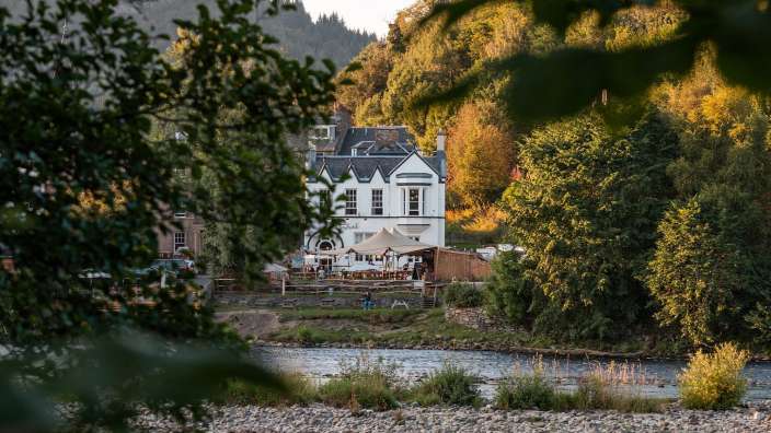 Ein weißes Gebäude neben einem Fluss mit einem Zelt davor