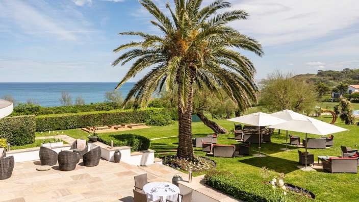 Ein Tisch und Stühle auf einer Terrasse mit Blick auf den Ozean