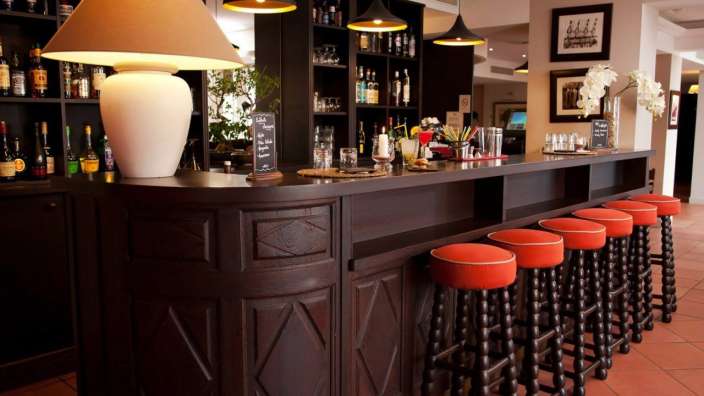 Eine lange Bar mit roten Hockern und einer Lampe