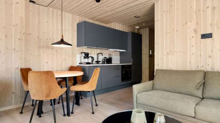 Ein Wohnzimmer mit einem Couchtisch und Stühlen neben einer Küche