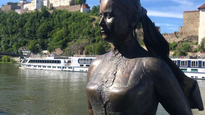 Eine Statue einer Frau steht neben einem Fluss