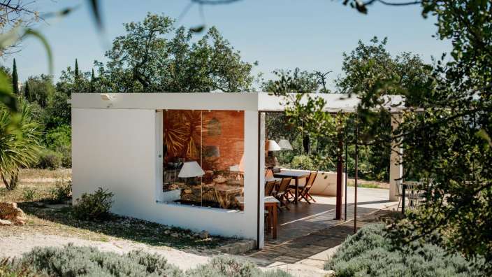 Ein weißes Gebäude mit einem Tisch und Stühlen darauf