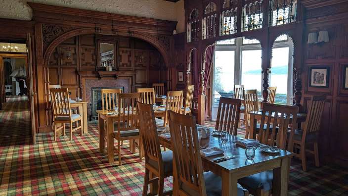 Ein Esszimmer mit Tischen und Stühlen und einem karierten Teppich