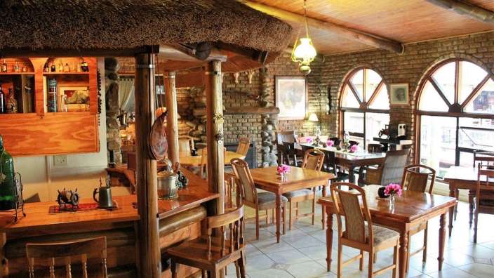 Ein Restaurant mit Tisch und Stühlen und einer Bar mit Strohdach