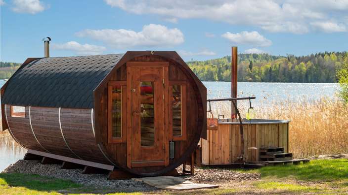 Eine Holzsauna mit einer Wanne neben einem See